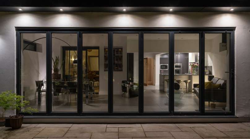 Stylish,,Bifold,Doors,At,Night,With,Downlighters,Revealing,Interior,Of